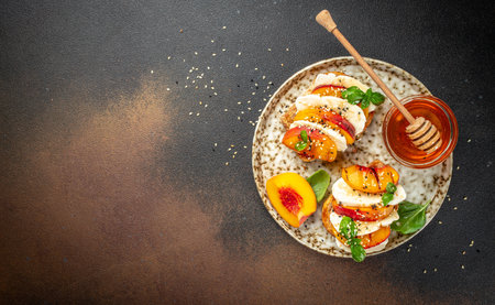 fruit caprese salad with peach, cheese and basil leaves on a dark background, banner, menu, recipe place for text, top view,の写真素材