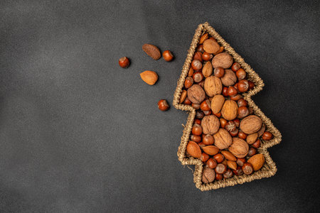 a set of nuts in a Christmas tree shaped basket on a dark background, banner, menu, recipe place for...
