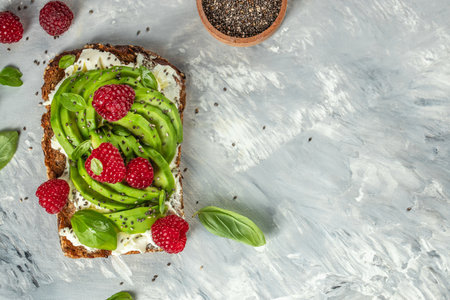 Whole wheat bread with avocado, raspberries, cream cheese and chia seeds, copy space, top view,の写真素材