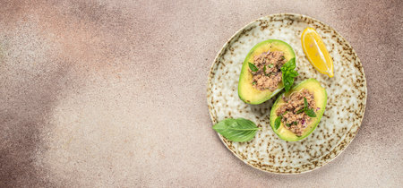 Tuna stuffed avocado on plate. Concept healthy and balanced eating. Long banner format. top view....