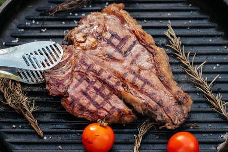 Beef T-Bone steak grilled porterhouse steak on barbecue grill with smoke and flames in green grass,の写真素材