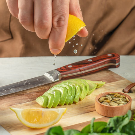 male hands squeezing lemon on avocado. cooking background.