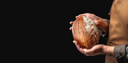 male baker holds homemade freshly baked rye gluten free bread, Long banner format. copy space for...