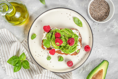 Avocado Toast for breakfast or lunch with avocado, raspberries, cream cheese and chia seeds. Vegetarian food. Clean eating. Top view. Copy spaceの写真素材