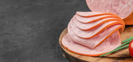 Ham meat sausages. Mortadella sausage slices on a wooden board, Long banner format. top view. copy space,の写真素材