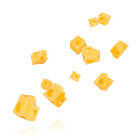 Pieces of cheese flying. Cheese cubes with holes levitating in air isolated on white background.の写真素材