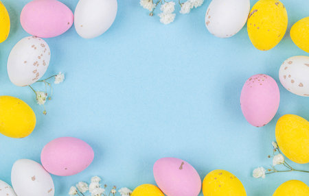 Colorful Easter Egg side border over a pastel blue paper background. Copy space.