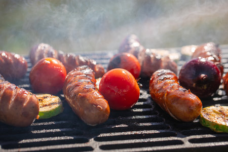 Hot sausage with vegetables on barbecue grill with smoke..の写真素材