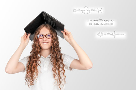 A playful young student wears a laptop like a hat, surrounded by chemistry formulas, capturing the fun, stress, and creativity of online learning.の写真素材