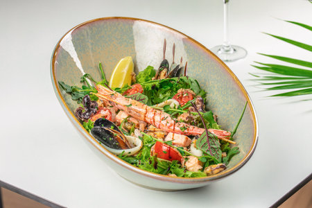 A fresh seafood salad with grilled shrimp, mussels, squid, salmon, and mixed greens, garnished with cherry tomatoes, lemon wedge, and herbs for a vibrant and healthy dish.の写真素材