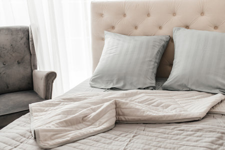 Modern bedroom interior with neatly arranged pillows and cozy bedding.