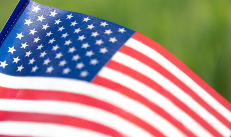 Close-up of waving American flag with stars and stripes on green background.