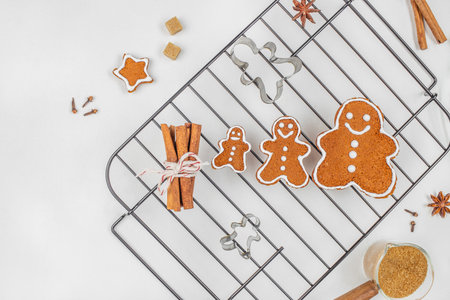 Freshly baked gingerbread cookies with icing on cooling rack and spices, top view. copy space.