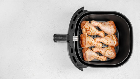 Raw seasoned chicken drumsticks in air fryer basket. top view. copy space.の写真素材