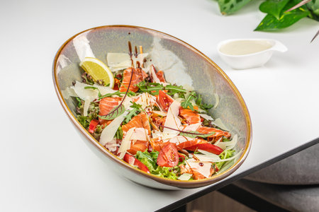 Fresh salmon salad with parmesan, arugula, and tomatoes served with lemon and dressing.の写真素材