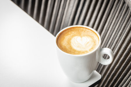 Cup of cappuccino with heart shaped latte art on a white table.の写真素材