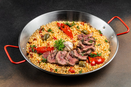 Paella with rice, red peppers, garlic, and capers in a traditional pan. top view.の写真素材