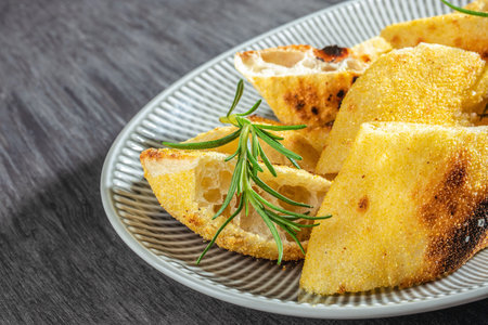 crispy focaccia bread slices with rosemary on a plate close up. top view.