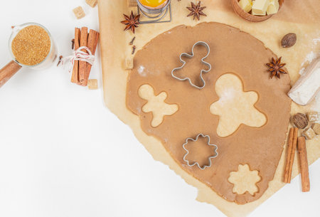 Gingerbread cookie dough with cutters, spices, and ingredients on kitchen table, top view, free...