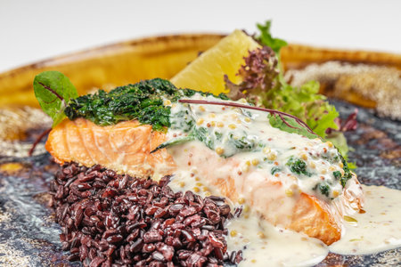 Grilled salmon fillet topped with creamy mustard sauce served with black rice and fresh greensの写真素材