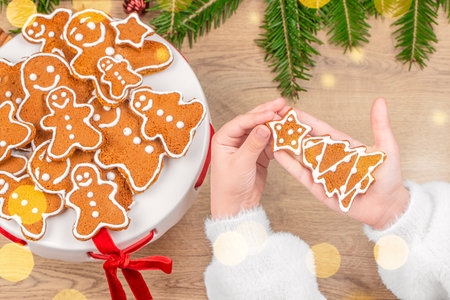 Child holding decorated Christmas gingerbread cookies with festive background and holiday atmosphere...