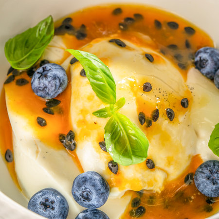 Vanilla panna cotta dessert topped with passion fruit sauce, fresh blueberries, and basil leavesの写真素材