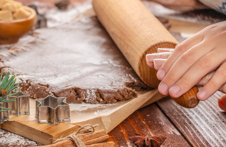 Close-up of young and elderly hands rolling out gingerbread dough together, symbolizing family connection, tradition, and shared holiday baking moments.の写真素材
