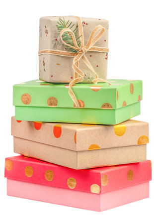 Stack of colorful gift boxes in green, red, and kraft paper with gold polka dots and natural twine ribbon, isolated on white background, symbolizing celebration and eco-friendly packaging.の写真素材
