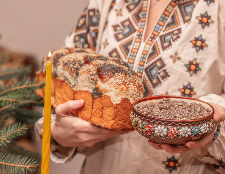 Traditional Ukrainian Christmas kutia and homemade bread in hands of woman wearing embroidered shirt, festive ritual meal of Holy Supper candle fir branches, authentic ethnic celebration scene..の写真素材