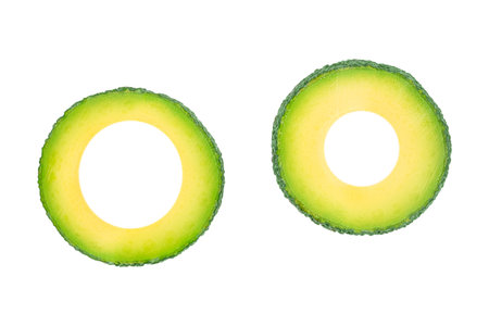 Two avocado rings isolated on white background, creative green tropical fruit slices with copy space for text, healthy organic food and minimalist design concept for advertising or bannerの写真素材