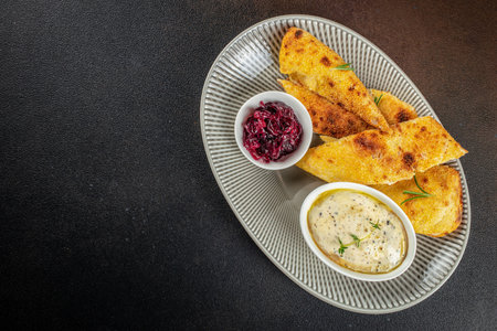Crispy golden polenta bread served with creamy herb dip and sweet caramelized red onion on an elegant plate dark background copy space for menu food advertising.の写真素材