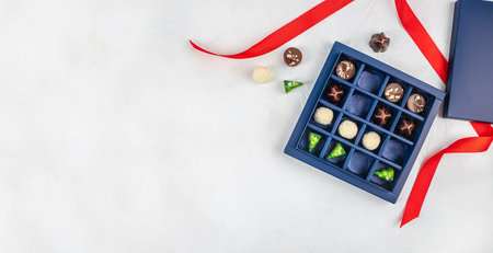 Top view of luxury assorted chocolate pralines in elegant blue gift box with red ribbon on white background and large copy space for holiday advertising.の写真素材