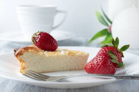 Breakfast with cheesecake, strawberries and a cup of tea on white dishes.の写真素材