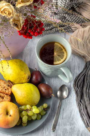 Still life with a cup of tea, a vase with a bouquet of dried flowers, fruit and a banana muffin.の写真素材