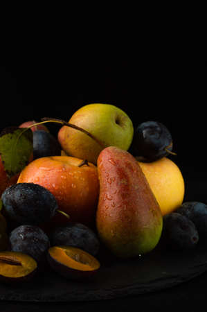 Still life of fruits on a black background.Pears, apples, plums.の写真素材