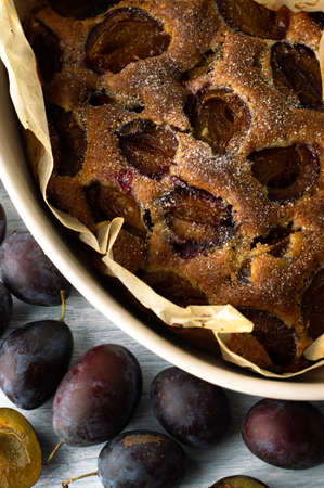 Pie with plums in a ceramic form on a light background with fruits.の写真素材