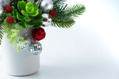 Composition Christmas with Christmas tree branches, silver and red balls, decor in a white ceramic vase on a white background with space for writing text.の写真素材