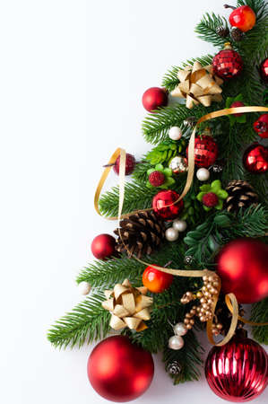 Fragment of a Christmas tree with decor in red-gold tones on a white background with space for writing text. Christmas card.の写真素材