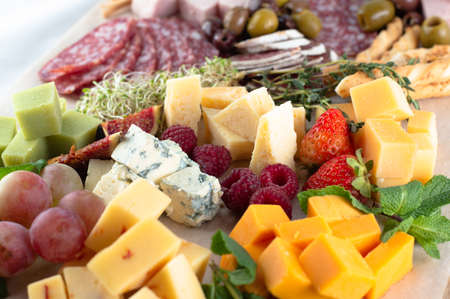 A varied cheese set with fruits, herbs and various meats.の写真素材