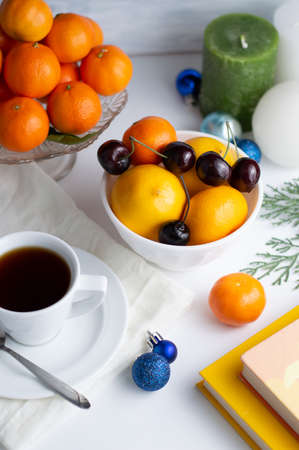 On a white background a cup with tea plates with tangerines, lemon and cherries, Christmas decor. Bokeh effect.の写真素材