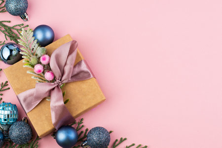 On a pink background with space for writing text, blue Christmas balls, green branches and a New Year's gift.の写真素材