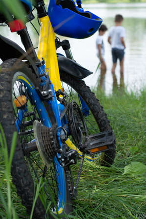 Blurred image of a bicycle in the foreground, in the background boys walking on the river bank....