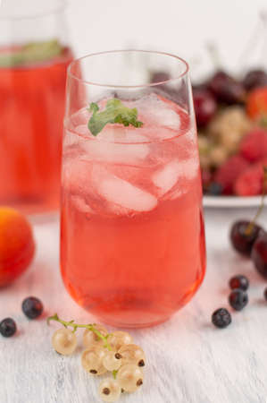 Blurred image of a fruit drink in a glass with ice on a background of fruits.Summer drinks concept.