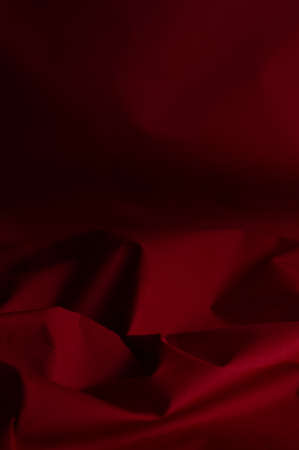 Blurred background of crumpled, burgundy-red fabric.Abstract, textural background.の写真素材