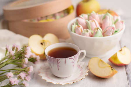 Blurred image of a cup of tea, marshmallows in a plate and box, cut apples.Natural, healthy dessert.の写真素材