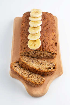 On a white background, banana bread with banana slices on a wooden board.Simple homemade food.