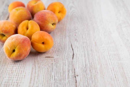 Blurred image of apricots and peaches on a light wooden background with space for writing text.の写真素材