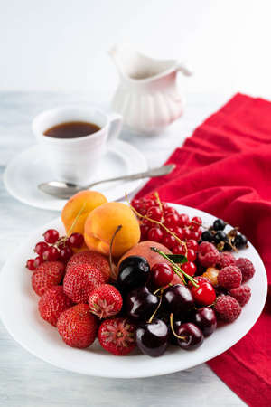 Fruits in a plate on a light table, a red napkin and a cup. Fruit background.の写真素材
