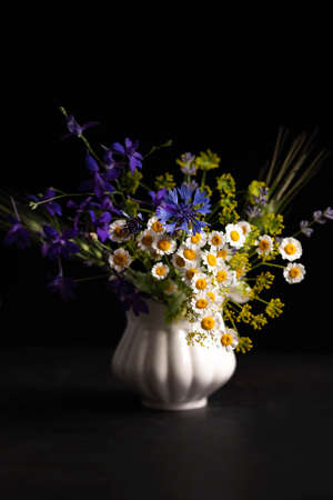 Blurred image of a bouquet with wild flowers on a black background. floral background.の写真素材