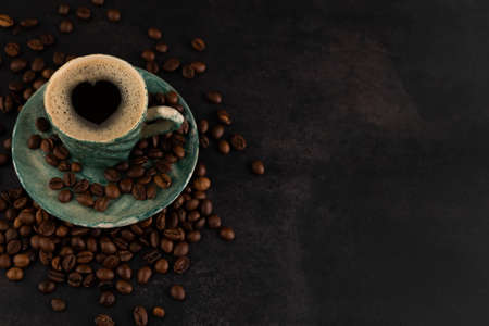 Blurred image of a cup of coffee and scattered grains on a dark background with space for writing text.Coffee love concept.の写真素材